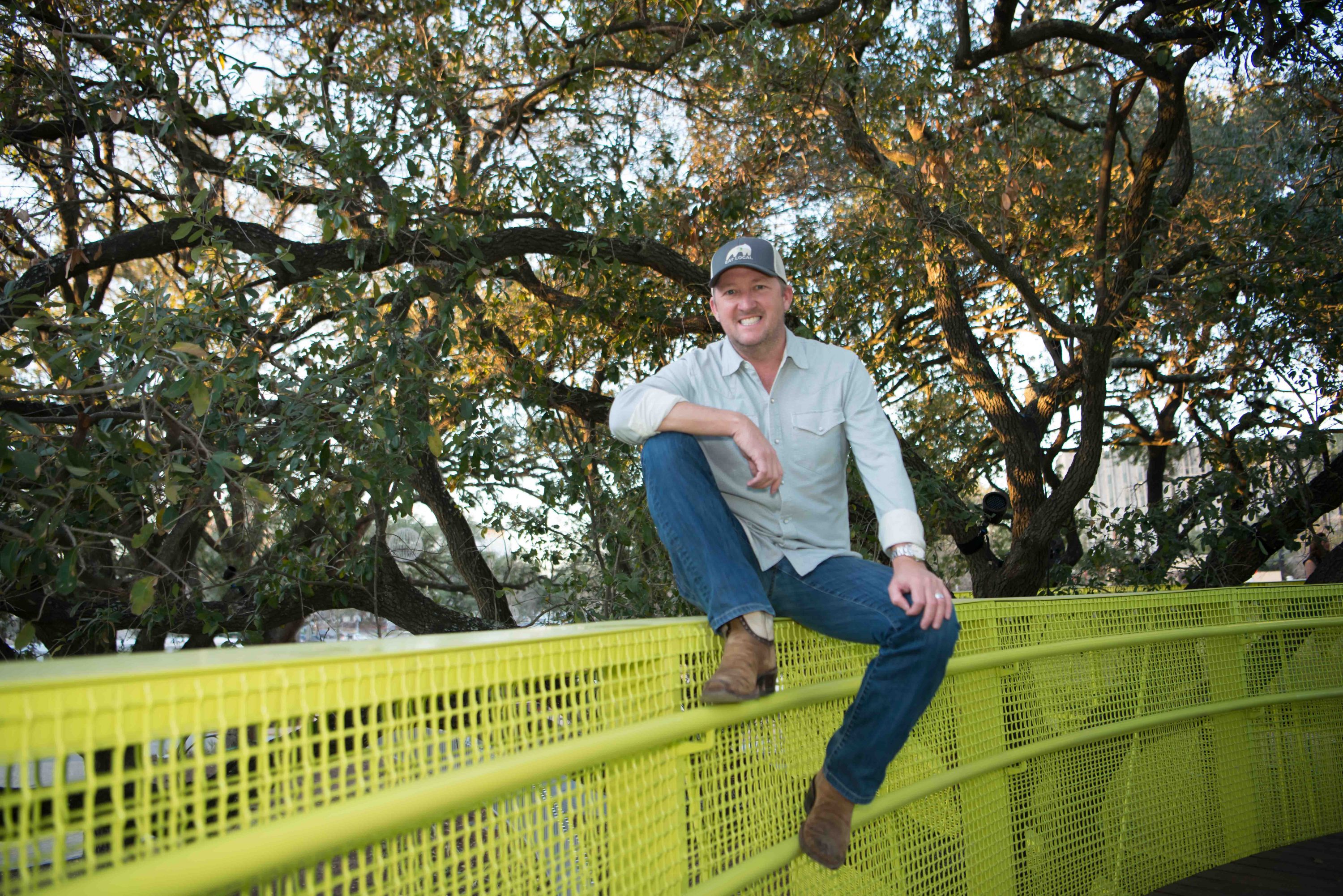 Chef Tim Love sits on a bridge in the newly renovated Levy Park. Love, who will debut three new restaurant concepts in the green space, hopes to soon host pop-up dinners on this very bridge. (Photo by Emile Browne)