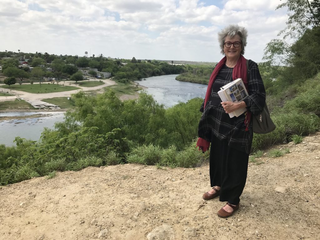 The author in Roma, Texas, on the bluff overlooking the Rio Grande. She carries Gerald Moorhead's "Buildings of Texas," a heavy and useful tome.