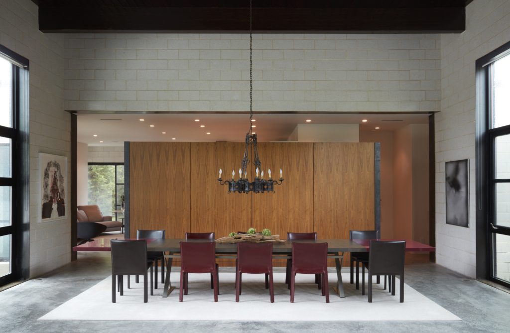 In the dining area, B&B Max Alto Max table with custom red lacquer leaves by James Ferrara. Vintage red leather Cassina Cab chairs by Mario Bellini. Floating book-matched walnut wall with hot-rolled steel frame by Ferrara. The French chandelier is 110 years old. From left: José Lerma’s "Untitled, #1," 2007, from Saatchi Gallery, New York; Jeff Zilm’s "Wife & Auto Trouble," 2014, from And Now gallery, Dallas.