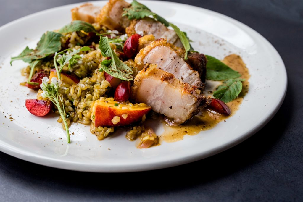 Pork belly with green farro, peaches, and spiced pork vinaigrette