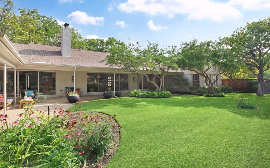 The backyard is complete with simple landscaping and lovely trees. 