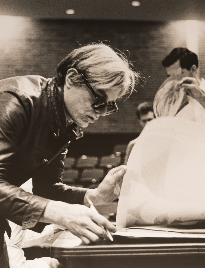 Andy Warhol in Pop cool, signing posters, University of St. Thomas, Houston, in what would turn out to be a turbulent year for him and the country — 1968. (Courtesy  Menil Archives, The Menil Collection, Photo Hickey-Robertson)
 
