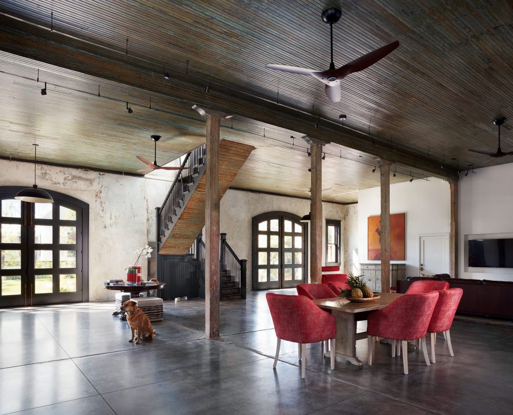 The original beadboard ceilings downstairs are 20 feet high. Vintage table and chairs, reupholstered in fire-engine red. The dog, Osso, was found abandoned on the property and adopted. 