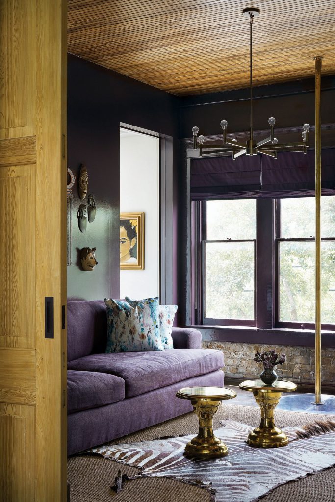 In the library, custom sofa covered in Holly Hunt velvet. Vintage brass tables. African zebra-hide rug. Antique brass fire pole. Vintage painting. 