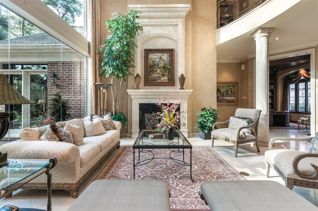 The spacious formal living room has a two-story ceiling complete with floor-to-celing windows and a wood-burning fireplace. 