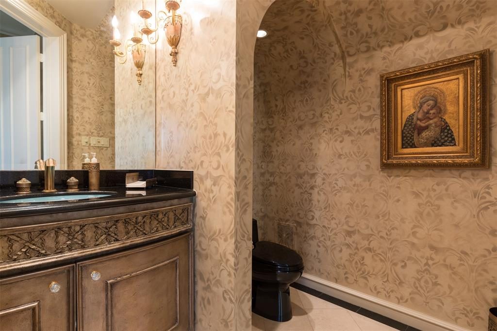 The powder room's vanity has a sleek lighted under-counter mounted glass sink and granite counter top. 