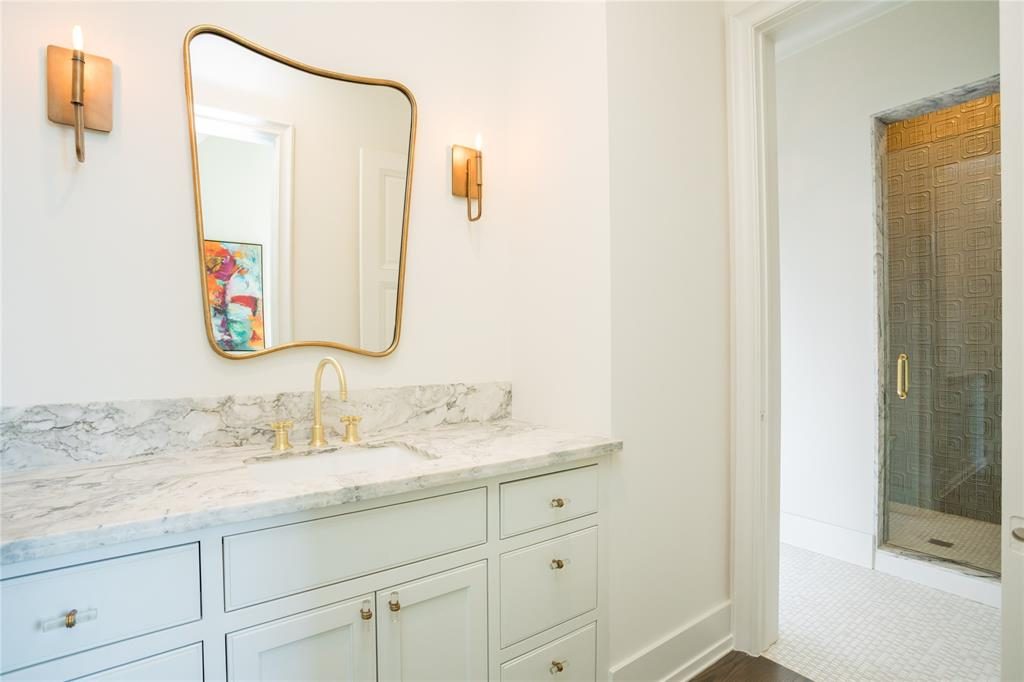 Porcelain sink vestibules sit beneath the gold-framed mirror of the secondary bathroom. 