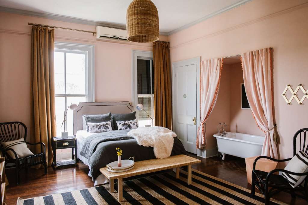 The Socialite is sprightly with pink tasseled curtains surrounding the tub and a striped rug. 