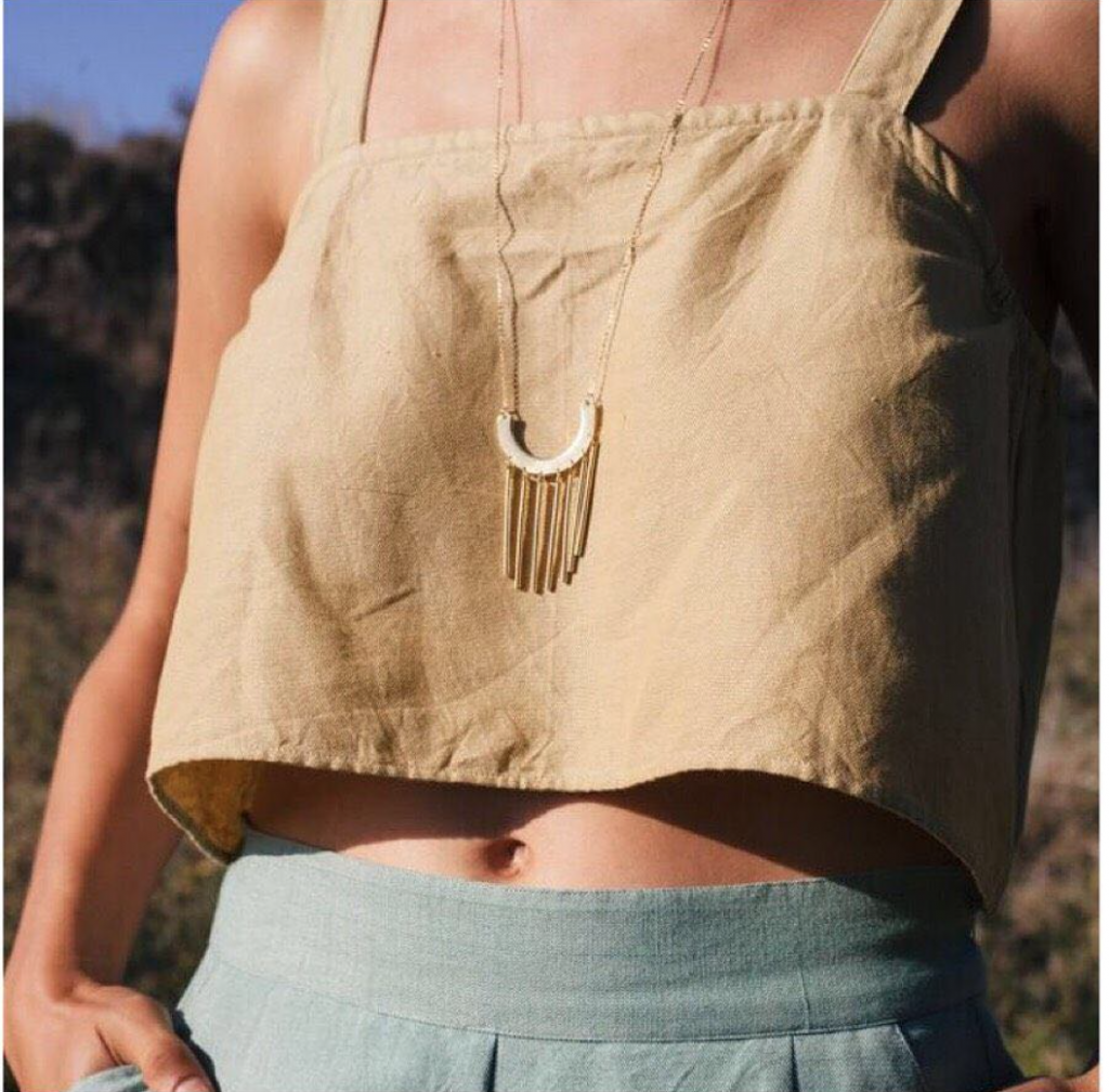 <a href="https://tribealive.com/shop/apparel/bandeaux-tank/"> Bandeaux Tank in Solid Marigold $68 </a> , <a href="https://tribealive.com/shop/jewelry/fringe-arch-necklace/"> Fringe Arch Necklace $52 </a> , <a href="https://tribealive.com/shop/apparel/cropped-pant/"> Cropped Pant in Pool Green $119.99-128 </a>