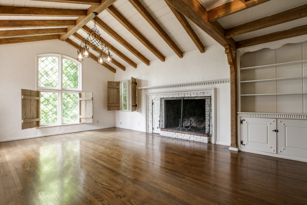 Living area of the University Blvd duplex with original beams, fireplace, and Dutch doors. The original chandelier was commissioned for the house by Dilbeck and created by Potter Iron Works. Courtesy Ebby Halliday Realtors 