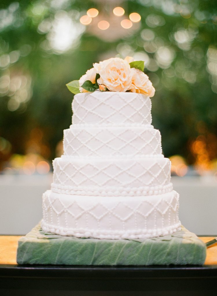 The four-tier wedding cake pulls in the garden theme with stunning yellow solidago on top, a native California wildflower. (Photo by Jose Villa)