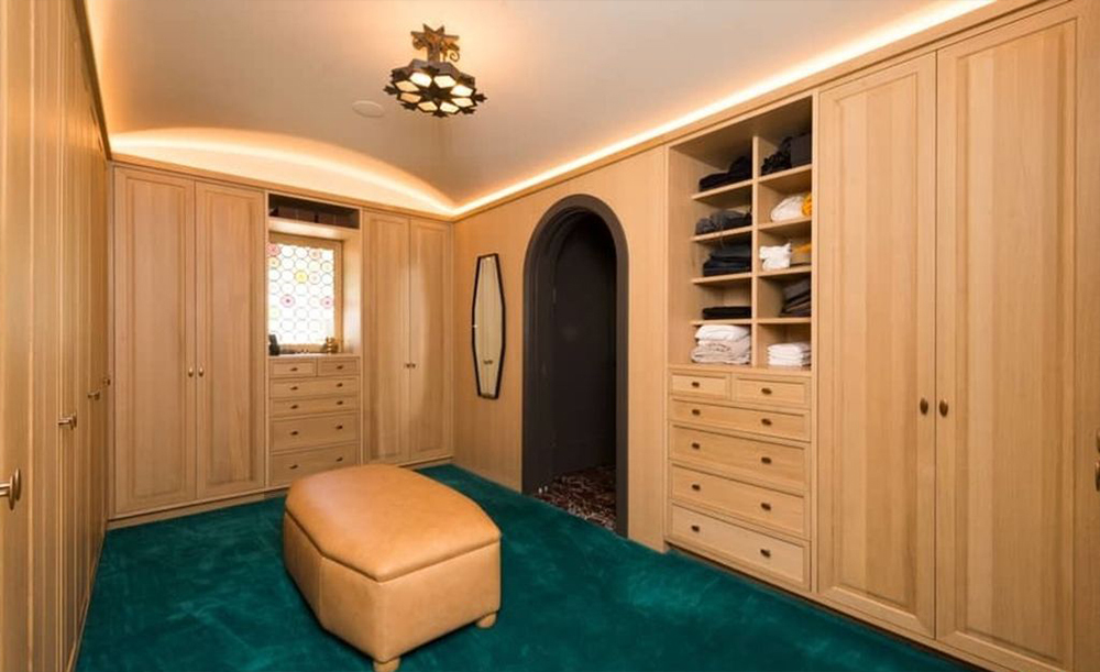 The closet has ample storage space, built-in wood wardrobes and a turquoise carpet. 