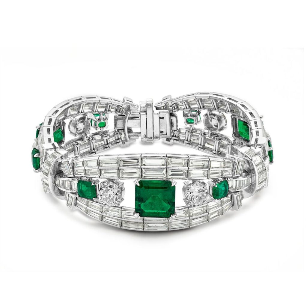 Hand-crafted in platinum, this Art Deco-inspired High Jewelry bracelet is a breathtaking heirloom with a dramatic design that showcases beautiful emeralds amid round and baguette diamonds. (13.25 ctw. emerald cut emerald, approx 30.0 ctw. round brilliant and diamond baguettes. Price on request)