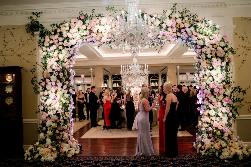 Guests mingle under a floral archway (Photo by Liz Banfield)