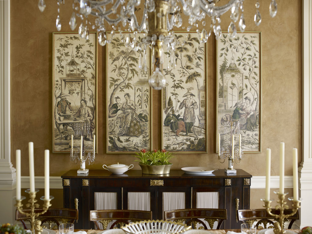 In a dining room, a quartet of grisaille chinoiserie panels above a Regency cabinet.