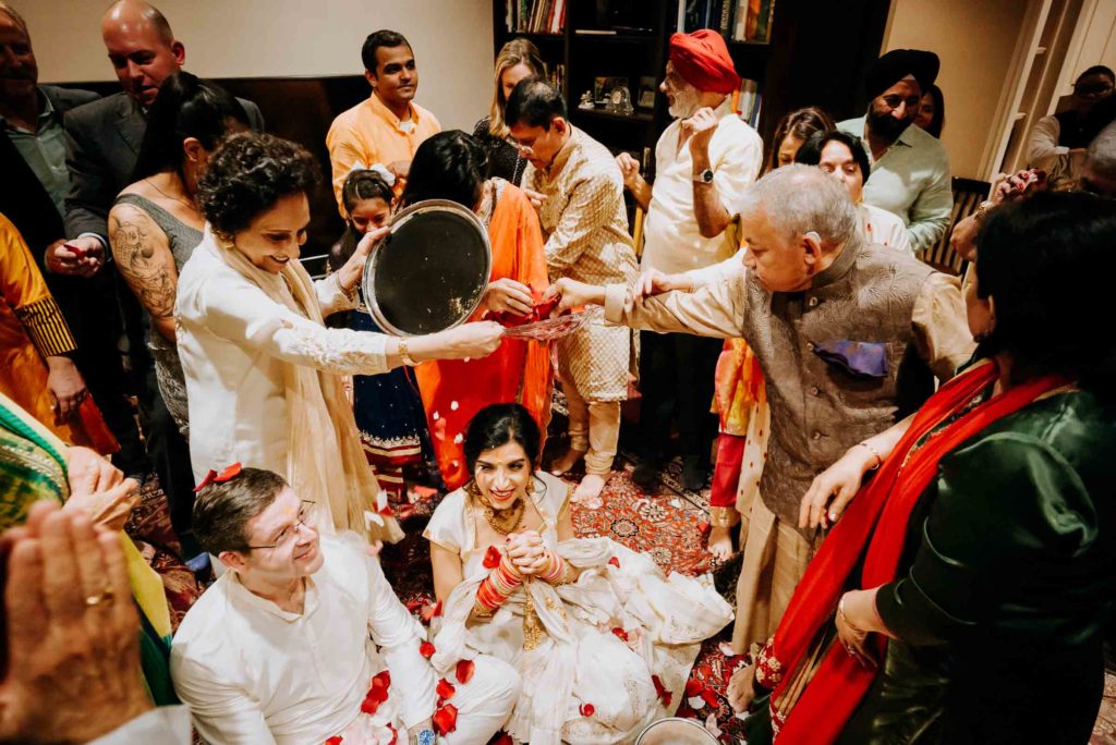 The soon-to-be bride and groom, Puja Verma and Gary Chapman, are doused in rose petals during the haldi ceremony.  (Photo by Philip Thomas)