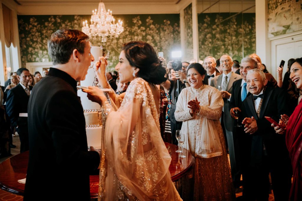 Kiran and Shiv Verma applaud as their daughter, Puja, offers her groom, Gary Chapman, a taste of wedding cake. (Photo by Philip Thomas)