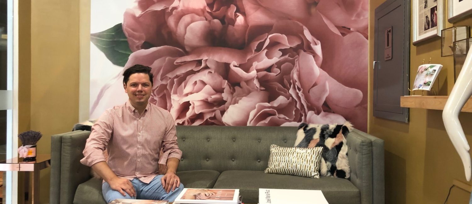 Designer David Peck in his showroom where one of his fabric designs has been translated into a wall mural, one aspect of his latest exercise in creativity.