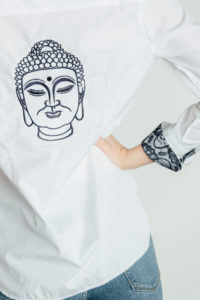 A hand-embroidered Buddha graces the back of an Audrey collection Ears of Buddha shirt.