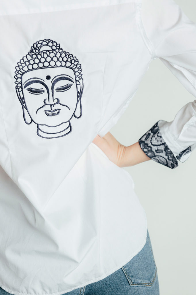 A hand-embroidered Buddha graces the back of an Audrey collection Ears of Buddha shirt. 