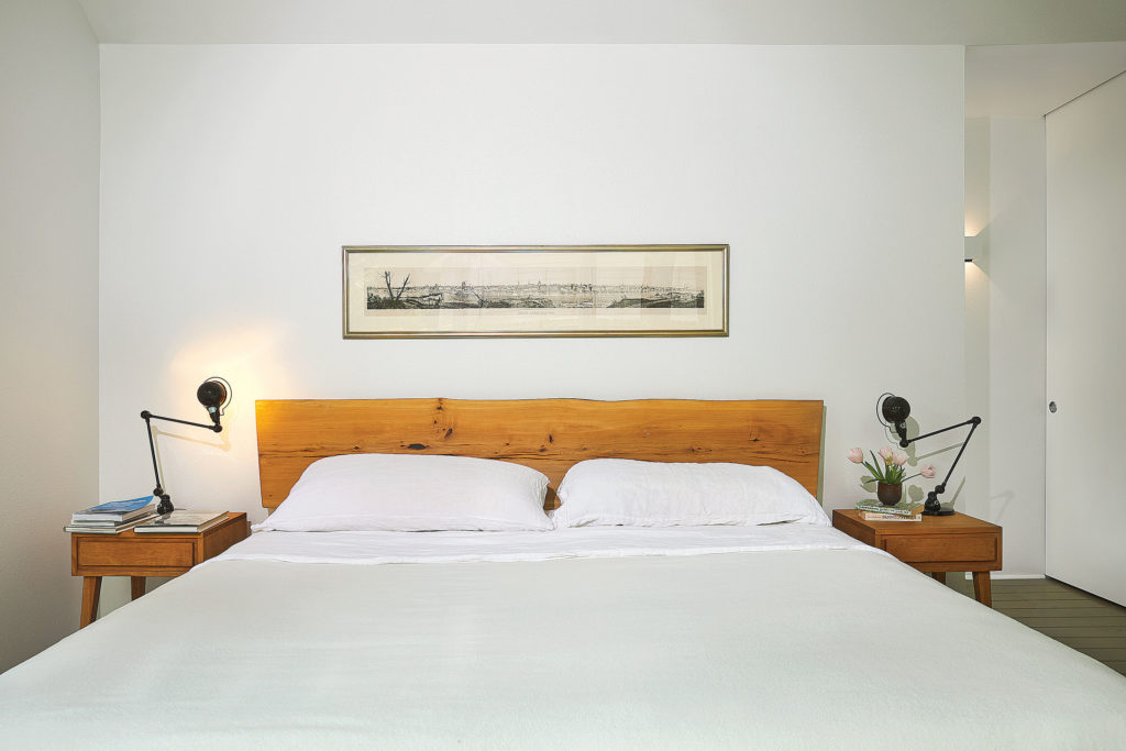 Bespoke bed from Dapwood in Albuquerque with a headboard made from a fallen elm tree. ModernMates birch side tables designed by Leslie Diamond for Conant Ball, 1947, from Cool Stuff. Glossy black Signal table lamps by Jieldé, designed in 1950, from Horne. Framed panorama shows an 1855 view of St. Louis where Koush went to high school. The teacup filled with tulips was a gift from the Hawaiian potter Toshiko Takaezu, who taught Ben’s mother in the 1970s. (Photo by Pär Bengtsson)