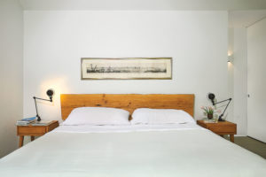 Bespoke bed from Dapwood in Albuquerque with a headboard made from a fallen elm tree. ModernMates birch side tables designed by Leslie Diamond for Conant Ball, 1947, from Cool Stuff. Glossy black Signal table lamps by Jieldé, designed in 1950, from Horne. Framed panorama shows an 1855 view of St. Louis where Koush went to high school. The teacup filled with tulips was a gift from the Hawaiian potter Toshiko Takaezu, who taught Ben’s mother in the 1970s. (Photo by Pär Bengtsson)