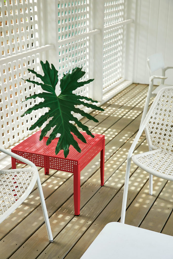In the dogtrot, white-painted lattice shades porch sitters from the western sun. Croisette armchair designed by Pascal Mourgue for Fermob. Dusty pink Självständig side table is from IKEA. (Photo by Pär Bengtsson)