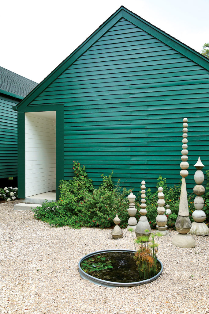 The carport, clad in old-fashioned beveled-pine siding milled in East Texas, forms a visual barrier to protect the side-facing courtyard from exposure to the street. Modular, cast-concrete Zygo-stem sculptures by Austin artist Paul Clarence Oglesby. Plants along the carport are red and yellow flowering — anemone, bat face cuphea, black-eyed Susan, butterfly weed, coreopsis, lantana, Turk’s cap, and ranunculus. The pond is a small galvanized stock tank planted with papyrus and yellow floating heart. (Photo by Pär Bengtsson)