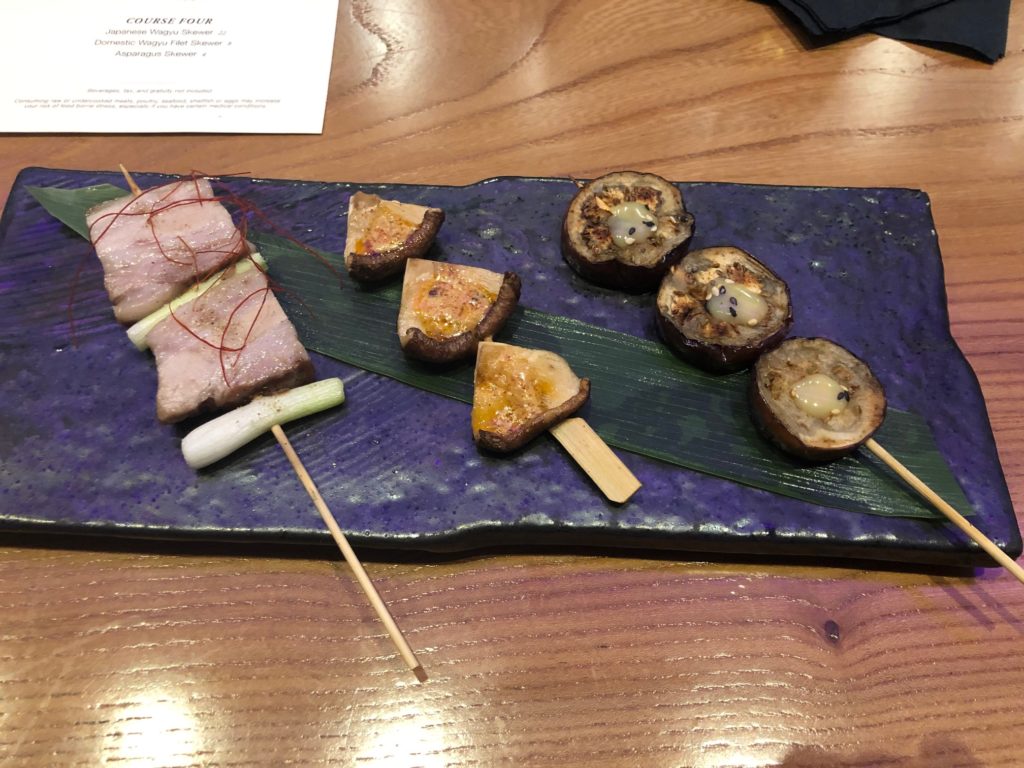 Roka Reserve's second course features Pork Belly Skewer, from left, Shitake Mushroom Skewer, and Eggplant Skewer.