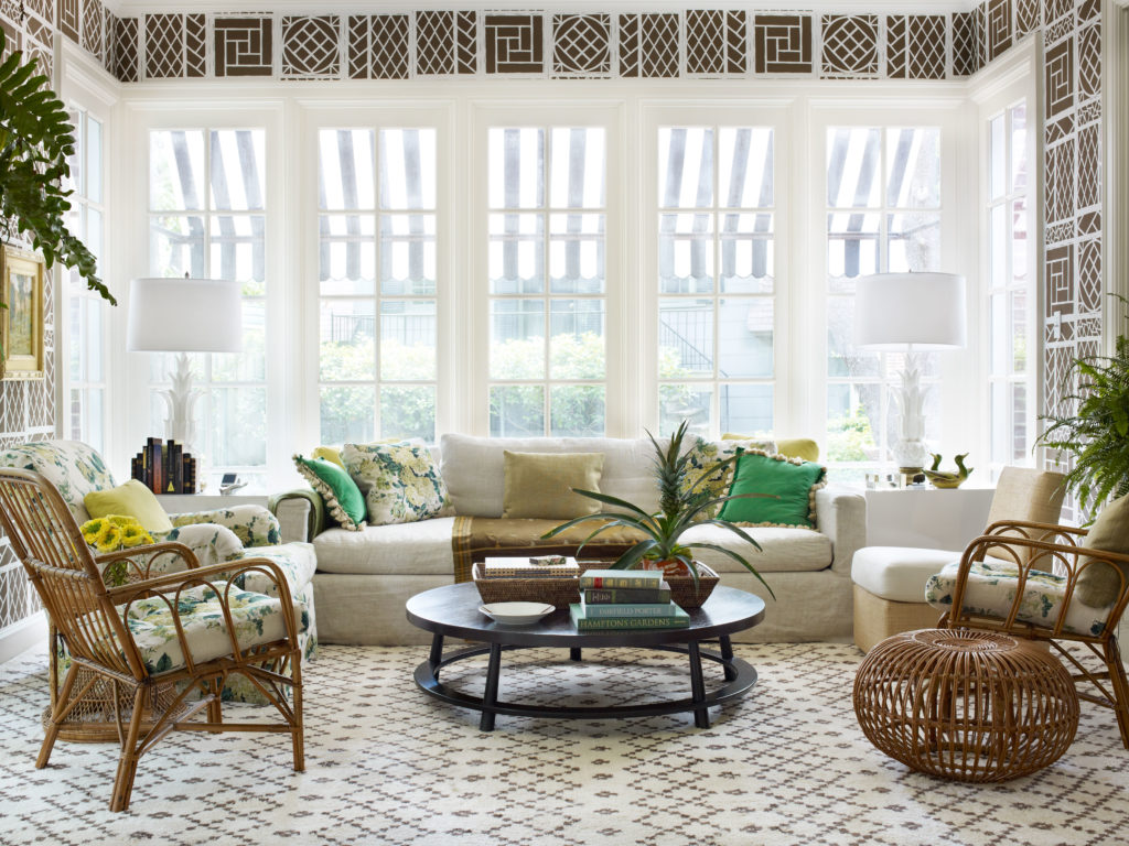 In a Dallas Highland Park home, Tom Scheerer rescaled and recolored his favorite Lyford Trellis wallpaper for the sunroom and adjacent dining room. Robsjohn-Gibbings coffee table, Billy Baldwin slipper chair, antique wicker, Restoration Hardware sofa, and custom Bridgewater chair. Side tables are painted plywood boxes.  (Photo by Francesco Lagnese)