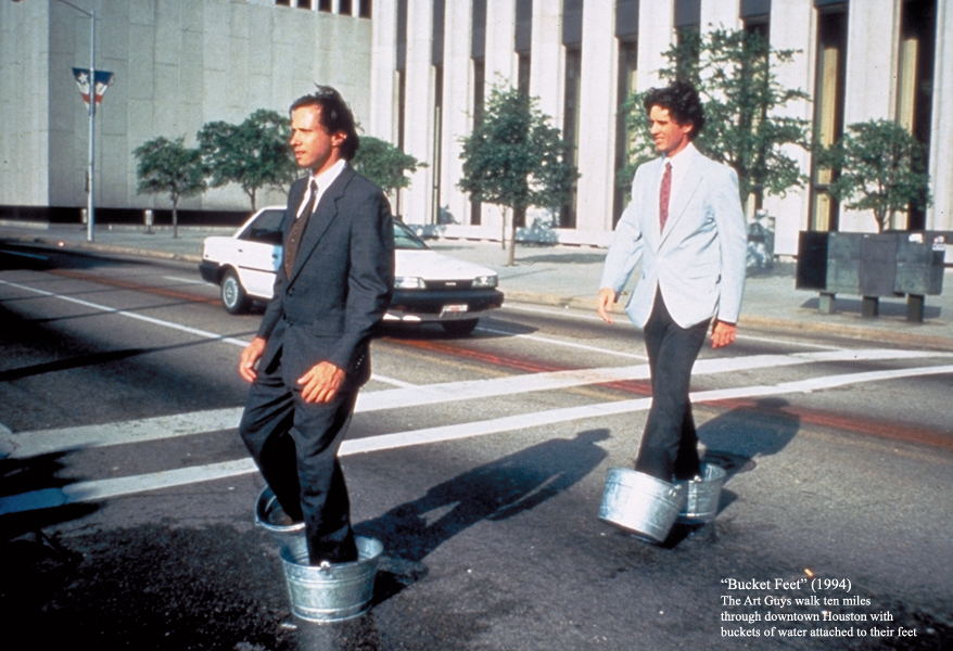A classic Art Guys performance, “Bucket Feet,” from 1994, hints at the artists’ debt to the Fluxus movement, which they literally brought to the streets of Houston. (Courtesy The Art Guys)