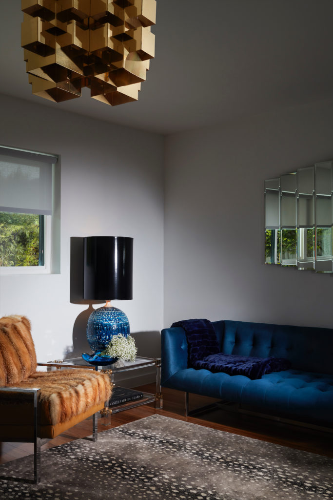 In the bedroom sitting area, Milo Baughman-style chrome chair upholstered in vintage fox fur. Stark rug. Ceramic 1960s lamp and 1970s mirror from James McInroe. (Photo by Lisa Petrole)