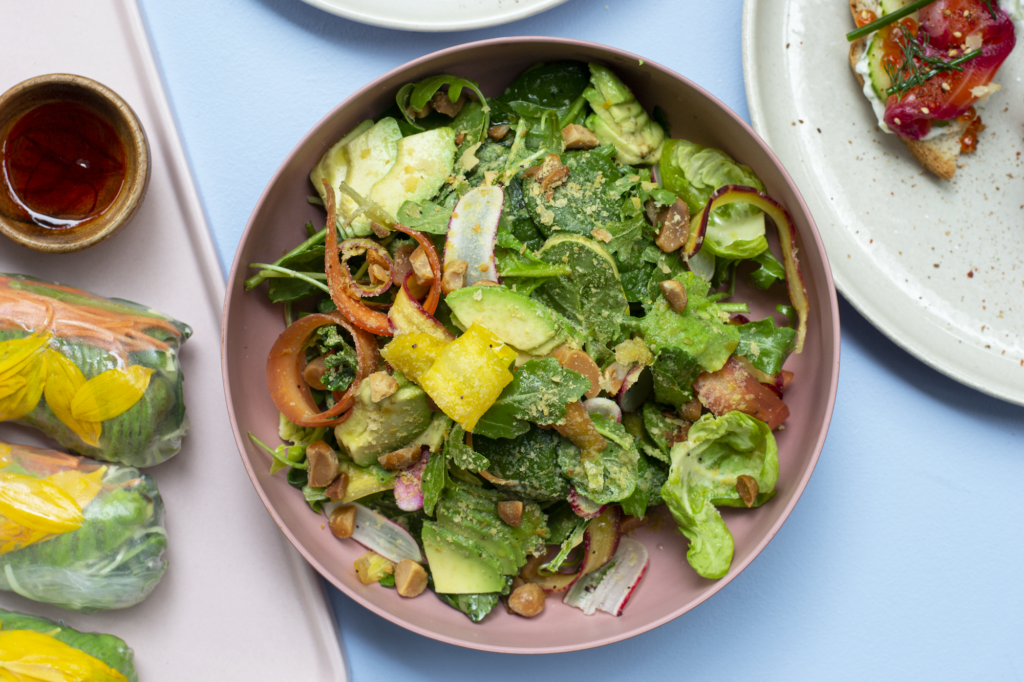 The Satisfying Salad is loaded with fresh greens, carrots, avocado, nutritional yeast, sprouted macadamia nuts, and topped with a Meyer lemon vinaigrette.
