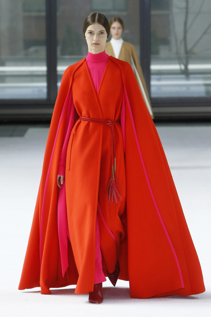 Carolina Herrera zinnia pink fluid crepe mock turtleneck dress with tie sleeve, cadmium red double face cape, red heeled boots. (Photo courtesy of Carolina Herrera)