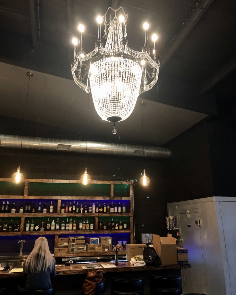 Tulane's black box style interior with purple and green back-lit bar and sparkling chandelier. 