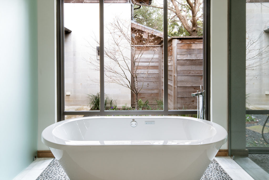 The master bathroom's soaking tub overlooks backyard gardens.