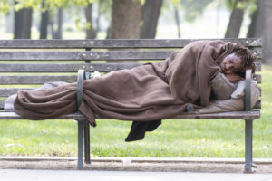 A person lays on a park bench across from Ben Taub Hospital as Harris County Judge Lina Hidalgo issued a “stay home, work safe” order in an effort to slow the spread of the COVID-19 coronavirus disease (Photo by F. Carter Smith)