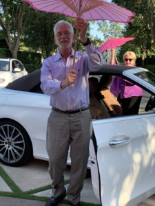 Dr. Jim Muntz and wife Anne pull out hot pink umbrellas for a brief second line parade around the drive.