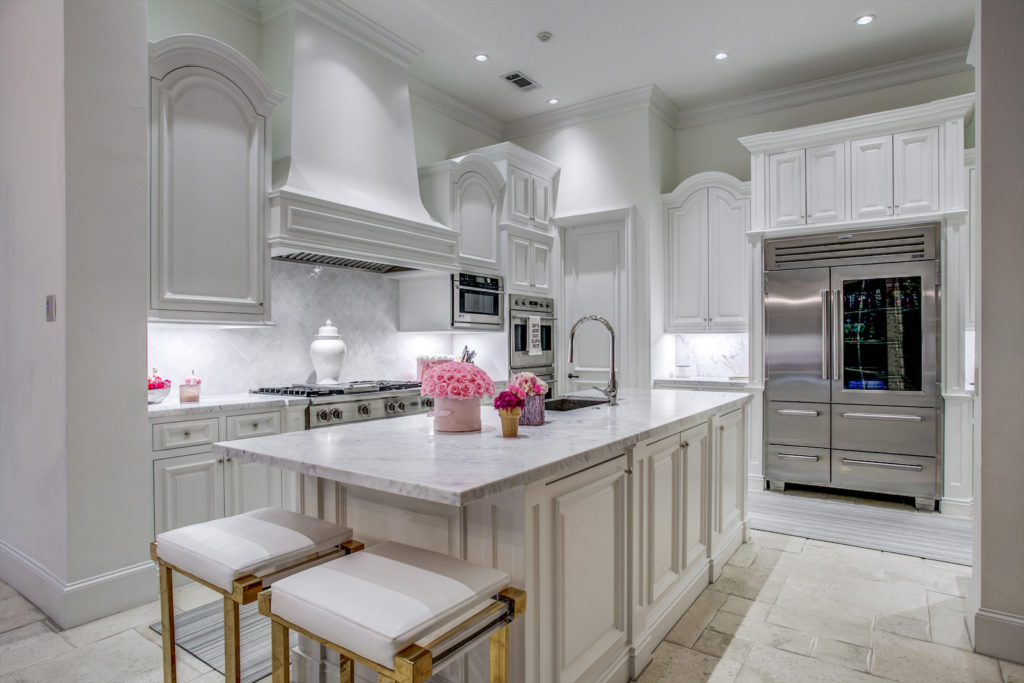 Even in the modern, all-white kitchen, punches of hot pink find their way in. (Photo by Compass Real Estate)