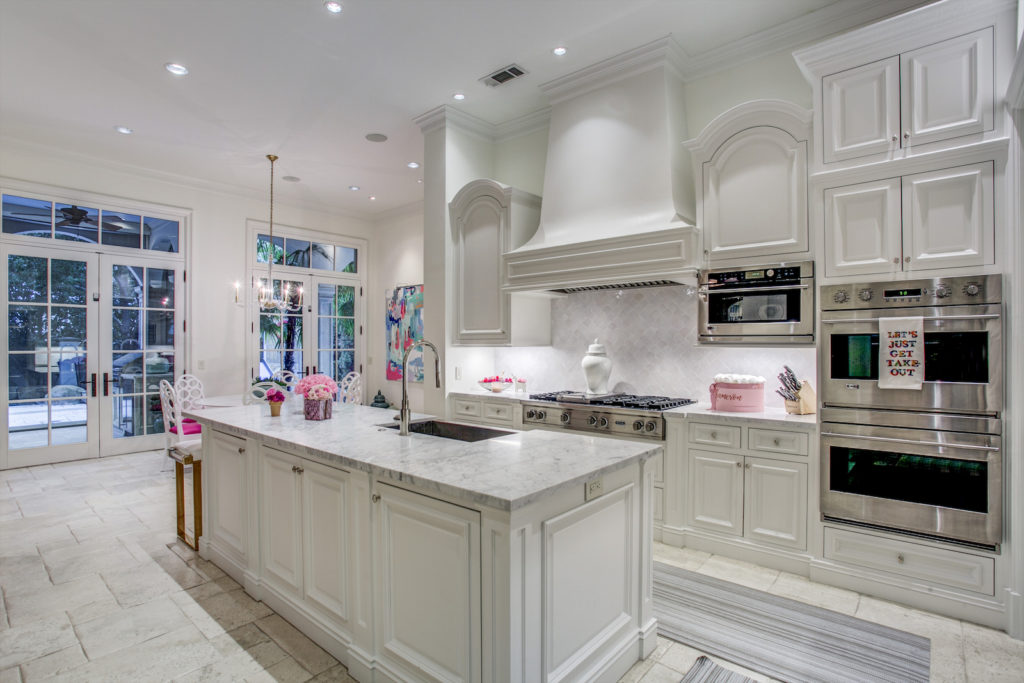 Even in the modern, all-white kitchen, punches of hot pink find their way in.  (Photo by Compass Real Estate)