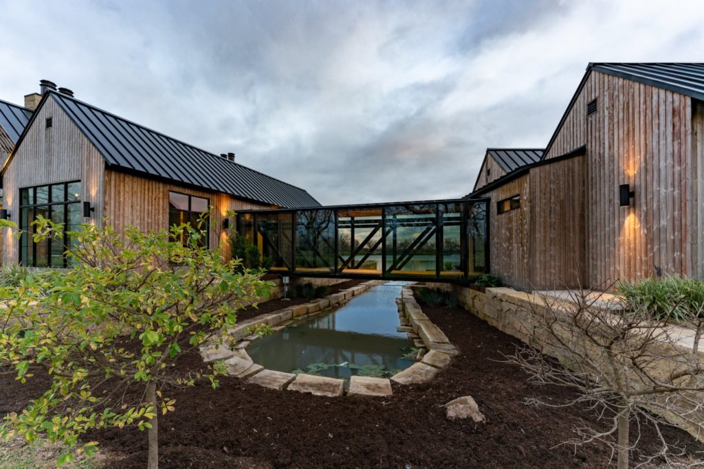 A steel and glass bridge in the Orchards at Pecan Acres home connects the master suite to the main house. (Photo by ProHouse)
