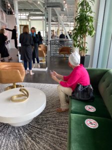 Bella Renova Salon client in a disposable towel waits on a sofa with clear social distancing markation.