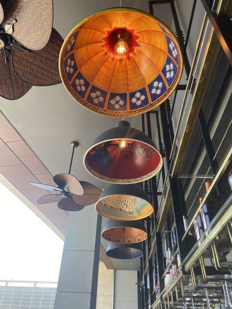 Custom, hand-painted lampshades hang from the ceiling of the outdoor lounge at Musaafer.