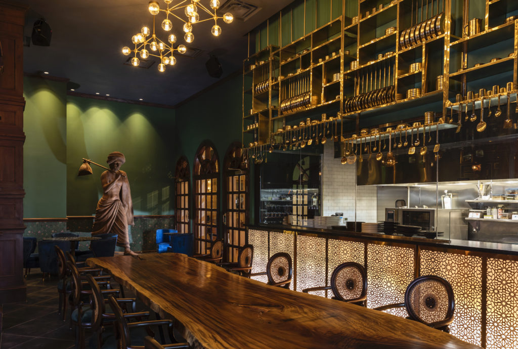 The Traveler's Room, the main dining room overlooking the dessert kitchen through a glass framed by a brass sculpture incorporating a massive rack of pots, pans and utensils. (Photo by Julie Soefer)