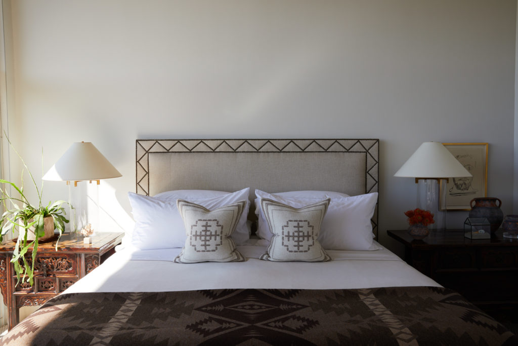 In the master bedroom, the brass nailhead design of the linen headboard by J. Randall Powers gives it a tribal vibe. Ralph blanket. (Photo by Pär Bengtsson)