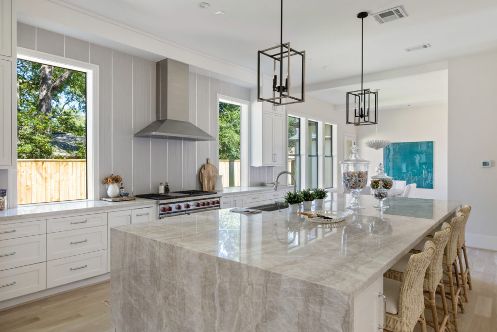 The kitchen features stainless steel SubZero and Wolf appliances with a gleaming quartzite island.