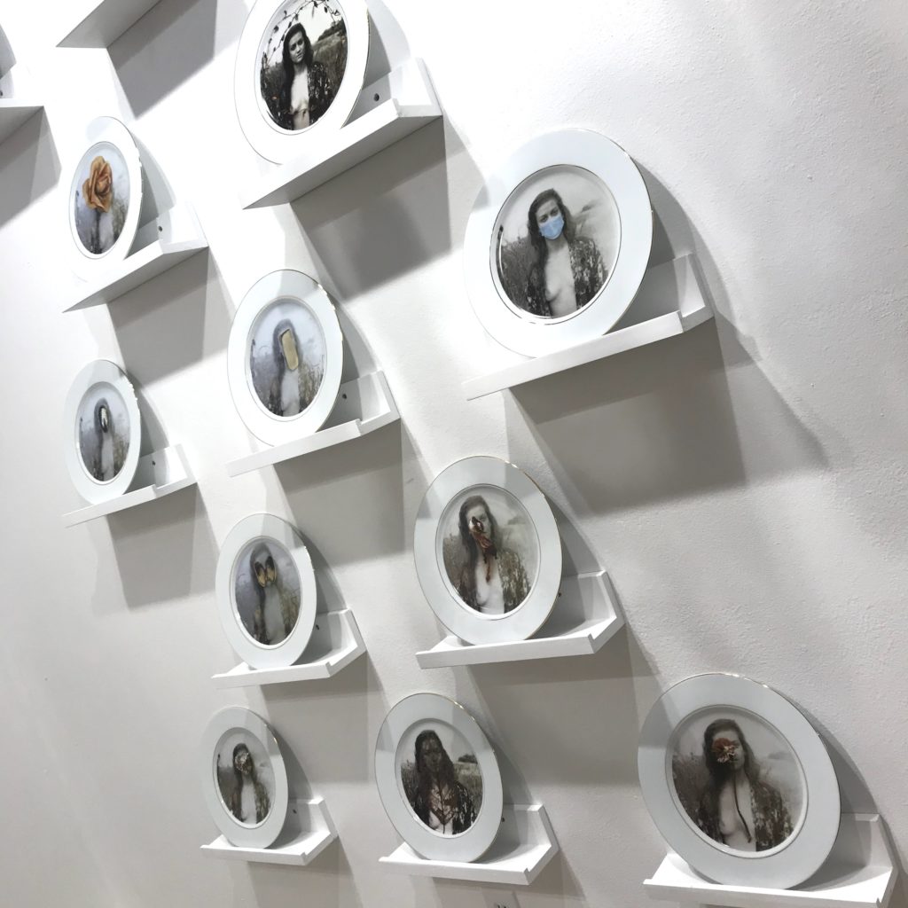 "Masks Women Wear" wall installation of a baker's dozen of gold-rimmed porcelain dinner plates, each with an image of a masked woman portraying such qualities as Fragility, Duty, Censure, Beauty, Chagrin, and Modesty. (Photo by Mary Margaret Hansen)
