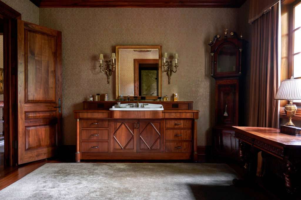 The gentleman's luxurious bath features  an antique sink cabinet and mahogany cabinetry and a glass and marble shower. (Photo by Nathan Schroder/Douglas Elliman)