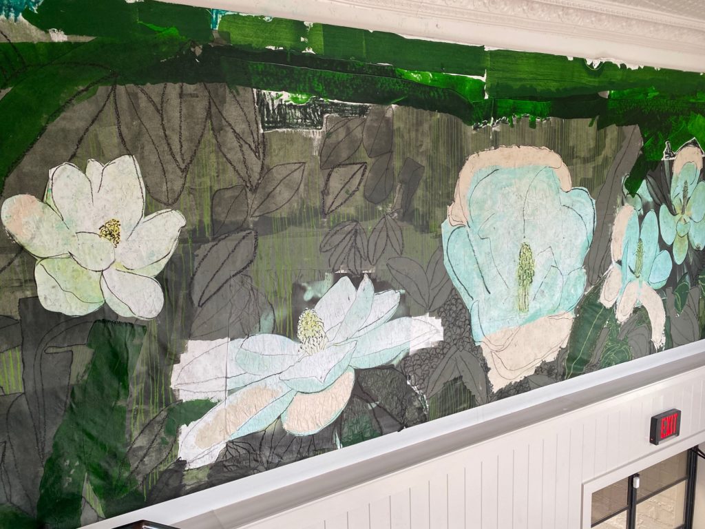 The magnolia mural by up and coming artist nine - foot mural by local artist Jonathan Paul Jackson welcomes guests to Bludorn.