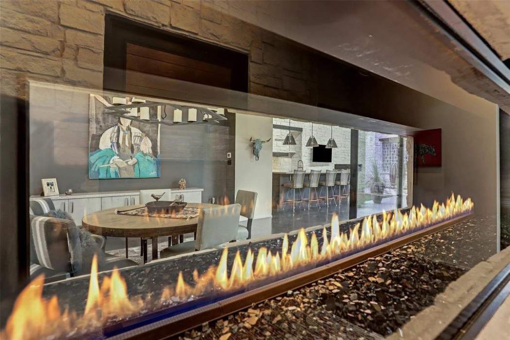 The double-sided 72" gas fireplace is inset in Austin White stone and separates the entry hall from the dining room.